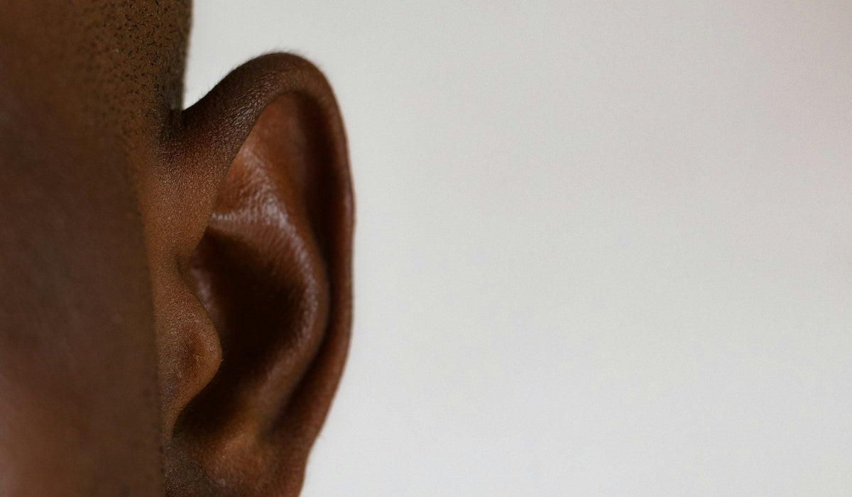 A close-up of an ear against a pale background, unpierced.