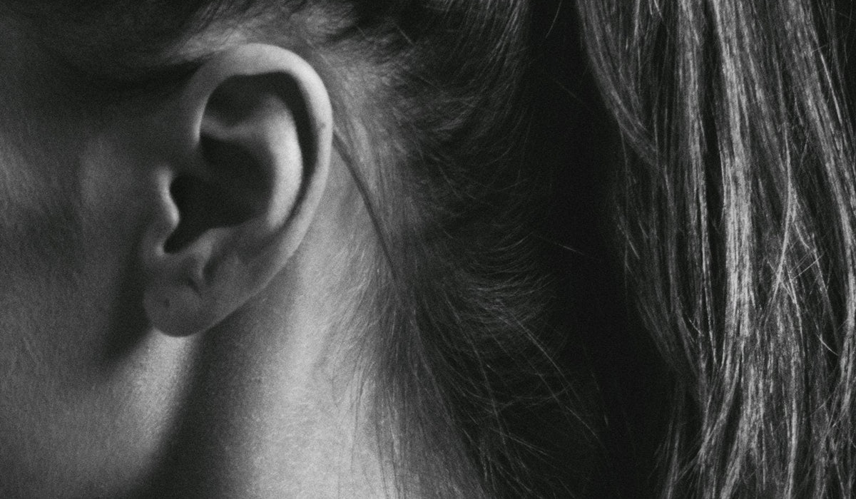 A close-up of an ear and the hair behind it, lit from the side.